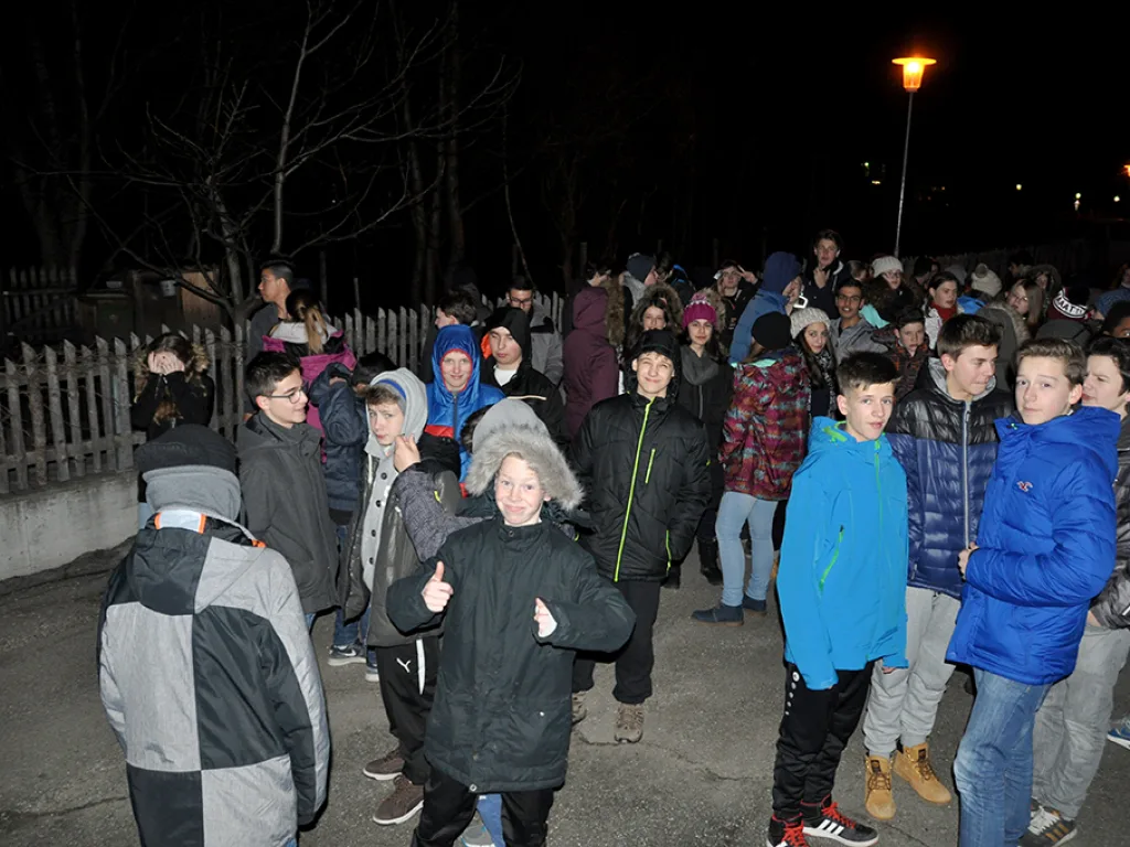 Große Gruppe steht abends dicht gedrängt an einem Zaun.